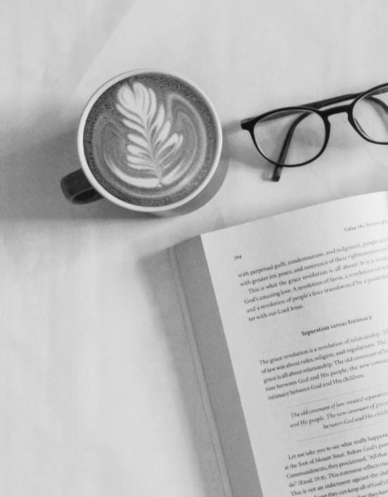 Un livre ouvert avec une paire de lunettes et une tasse à café